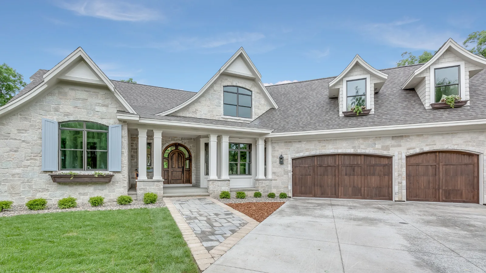 Light stone home with blue shutters and gray architectural shingle roof
