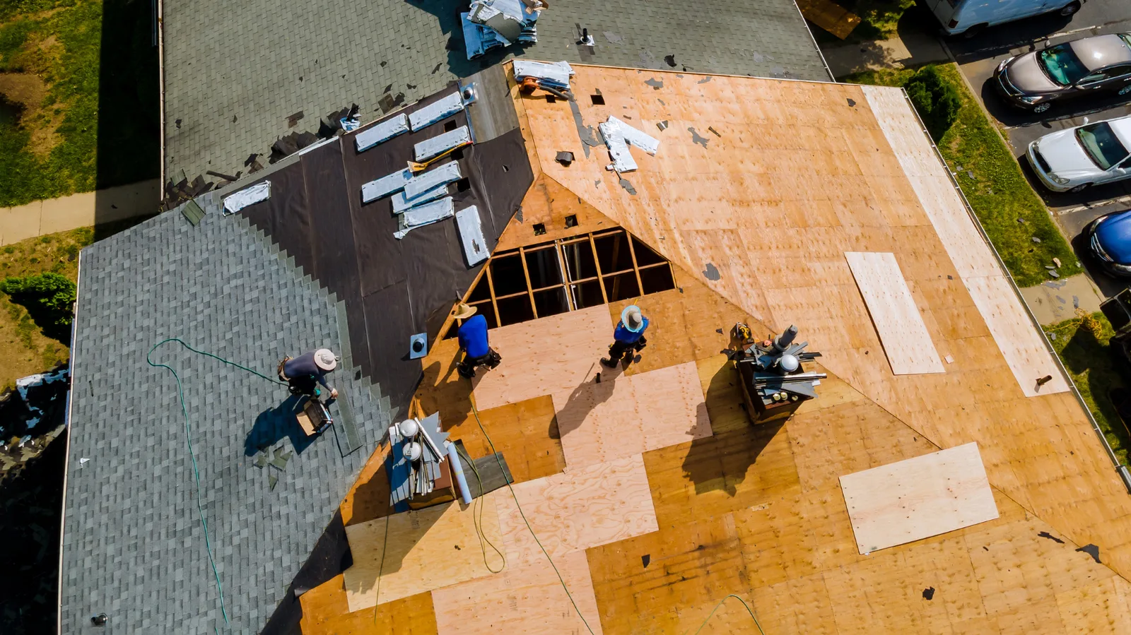 Overhead view of roofers replacing shingles on a large roof